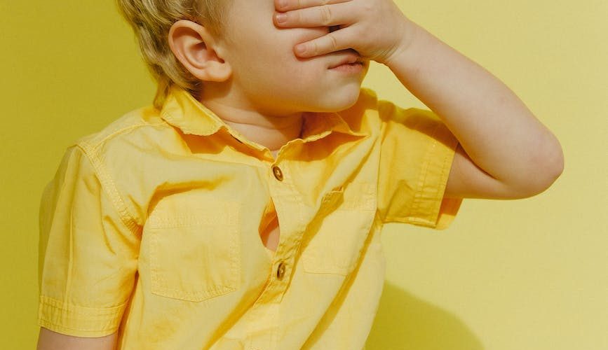 photo of a boy covering his eyes